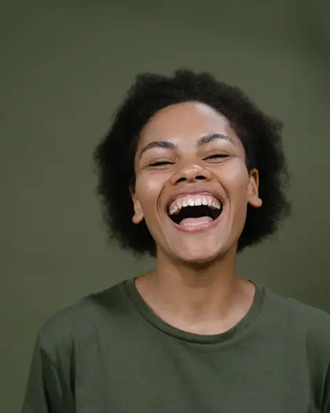 A woman laughing against a green studio wall