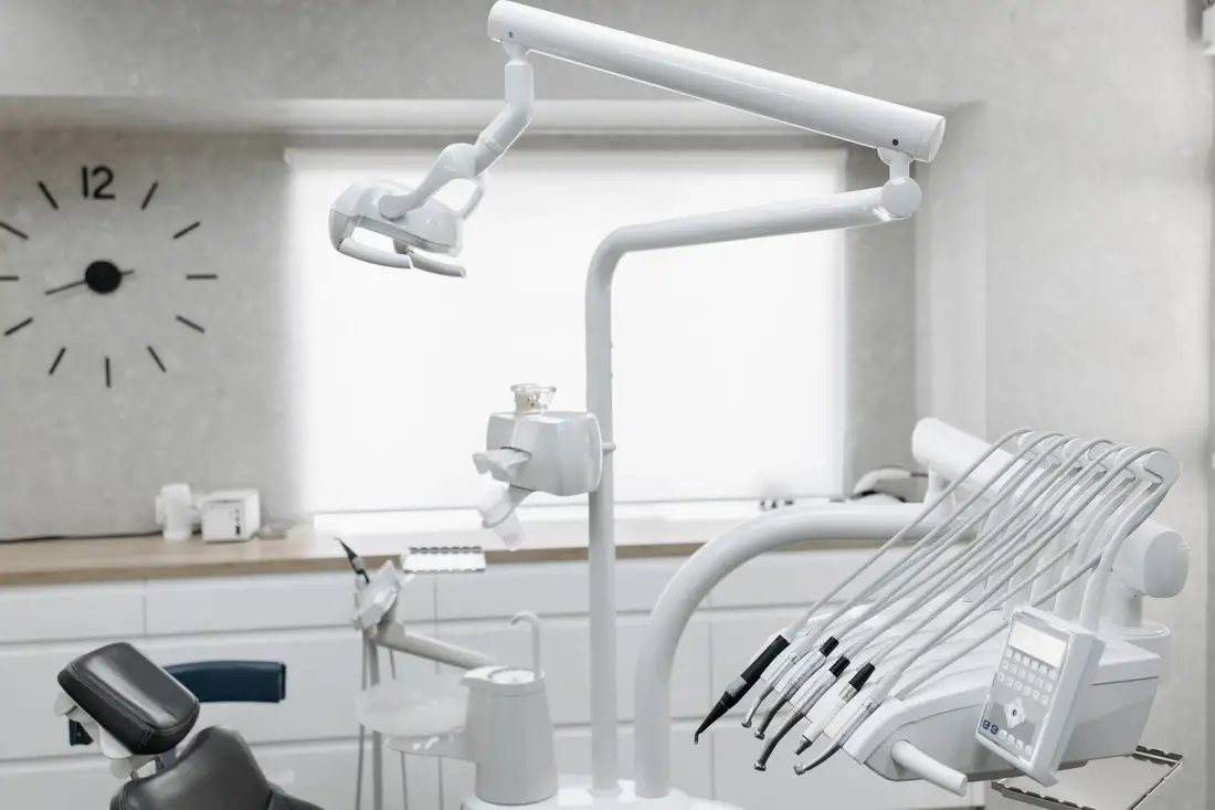 A bright treatment room with a dental chair, overhead light and instrument tray
